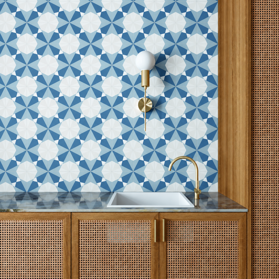 Altea Blue Taco geometric wall tiles behind a white basin with brass fittings and woven cane cabinetry.