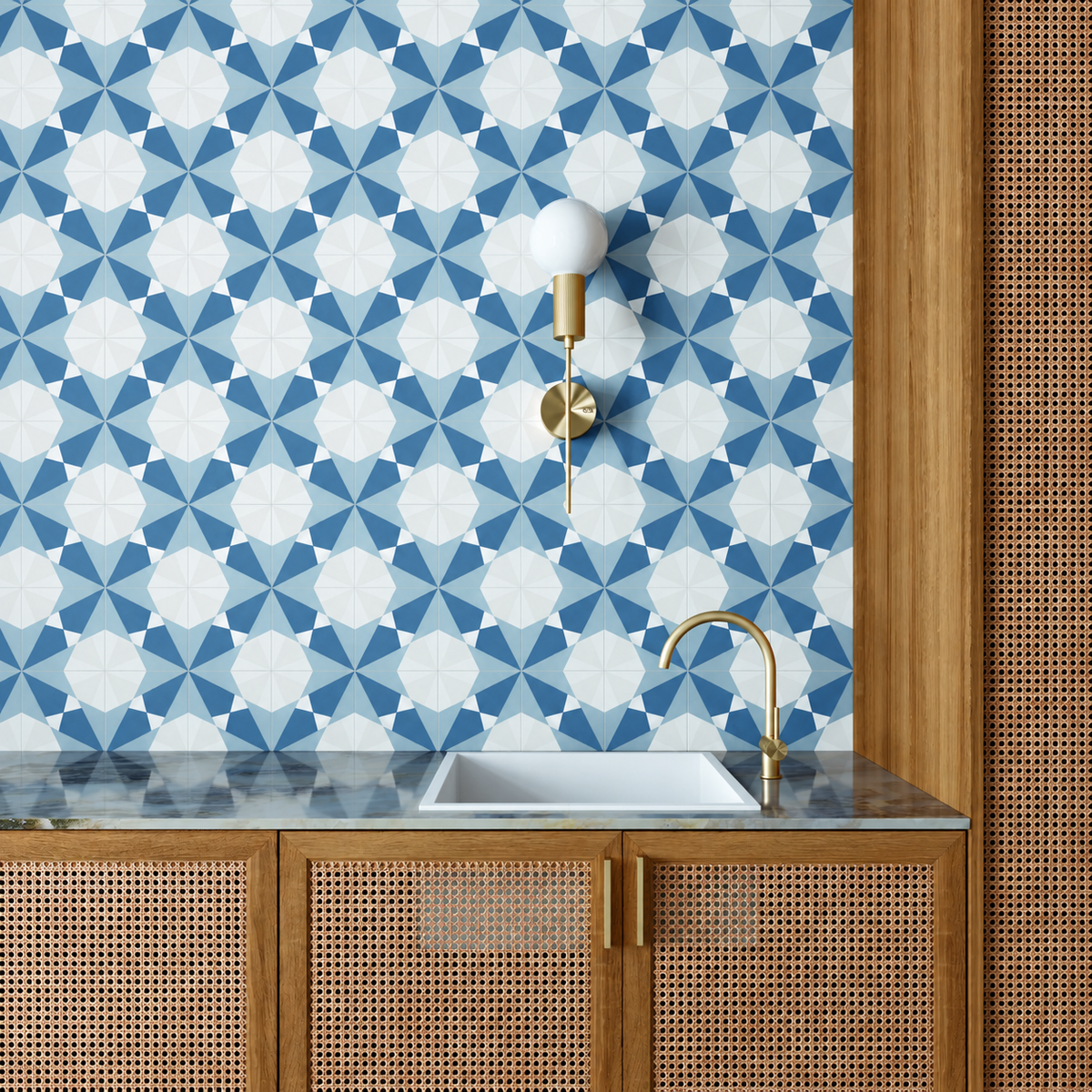 Altea Blue Taco geometric wall tiles behind a white basin with brass fittings and woven cane cabinetry.