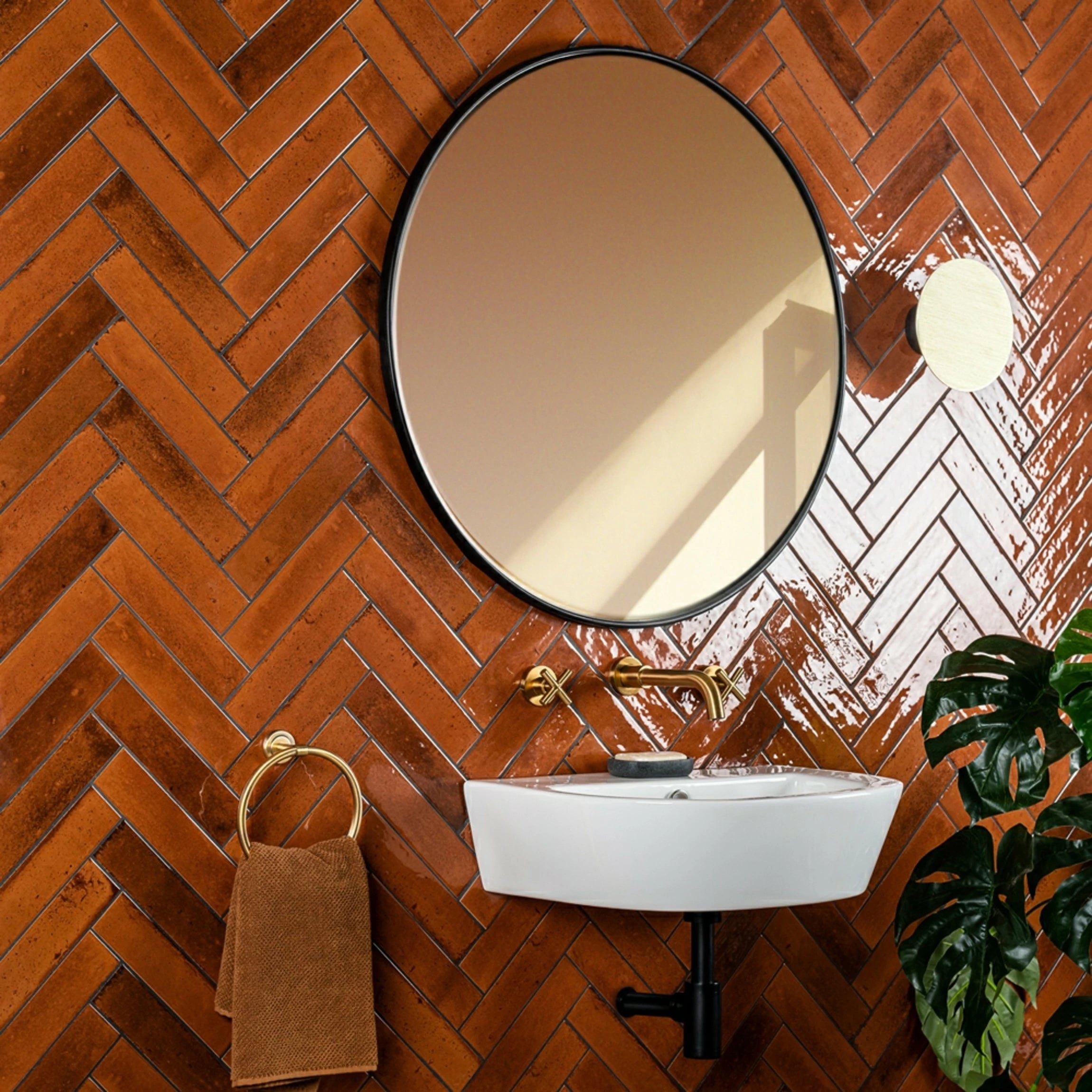 The wall is covered in gloss red  terracotta metro herringbone tiles, 