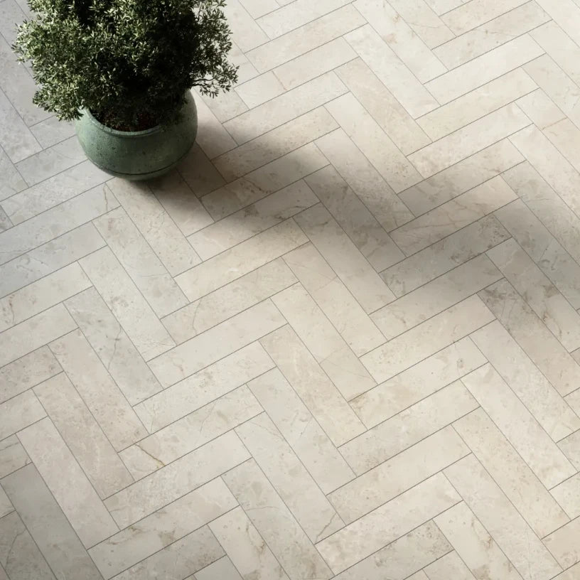 Botticino Beige honed marble herringbone floor tiles with warm cream tones and subtle veining in an elegant interior setting.
