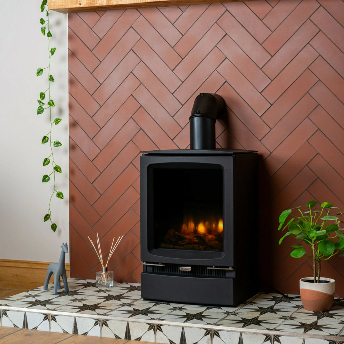 Black freestanding stove against a herringbone-patterned wall with decorative elements.