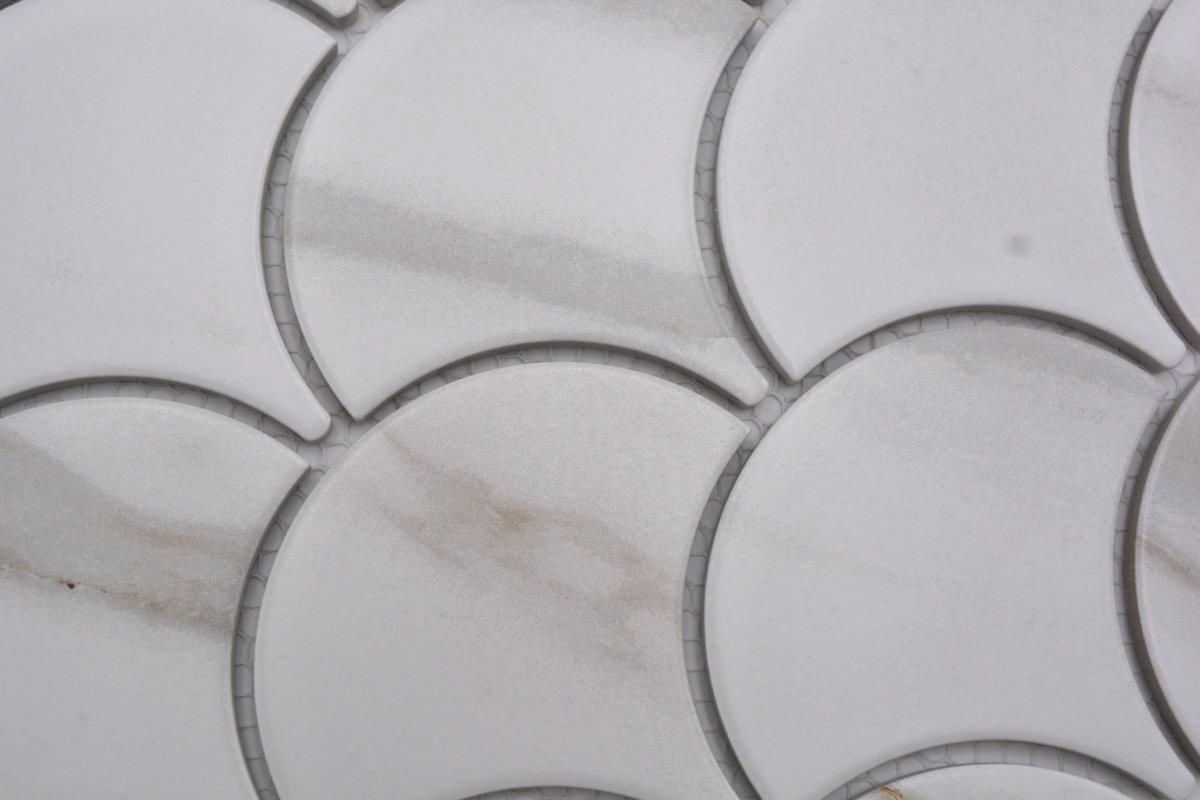 Macro detail of white and gold marble effect scallop mosaic tiles showing curved fan pattern, mesh backing and 2mm joints