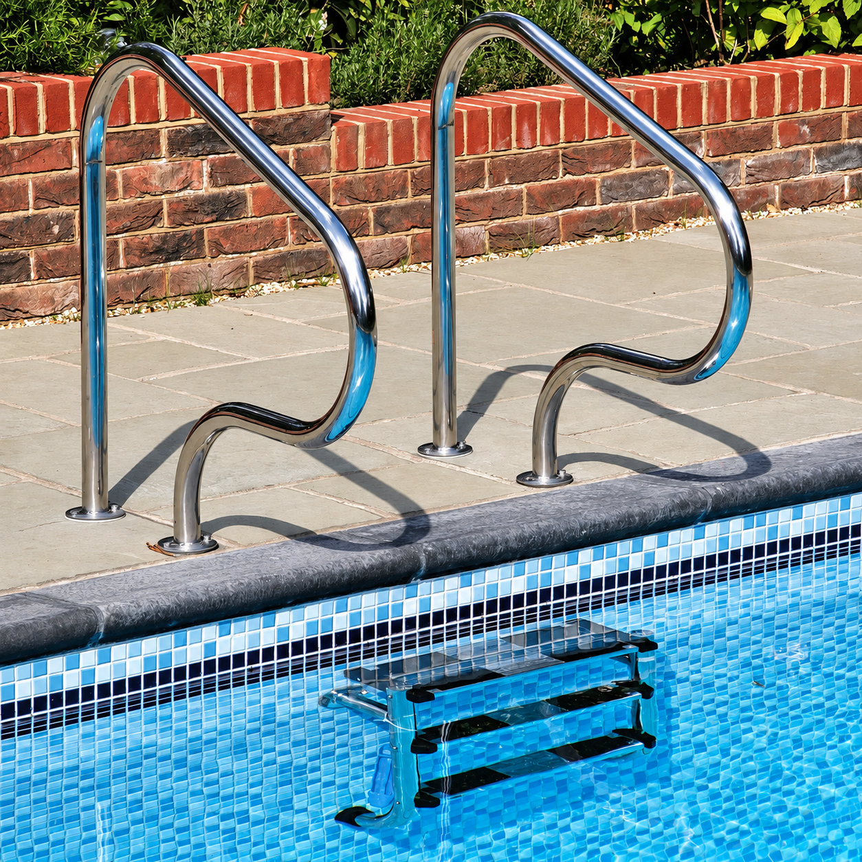 Ceramic Pool Caribbean blue and white mosaic tiles lining an outdoor swimming pool beside stainless steel access steps.