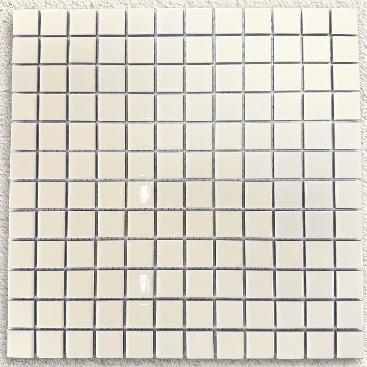 Close-up of Ceramic Pool Vanilla Mosaic Tile showing 23 × 23mm cream squares, gloss reflections and mesh backing.