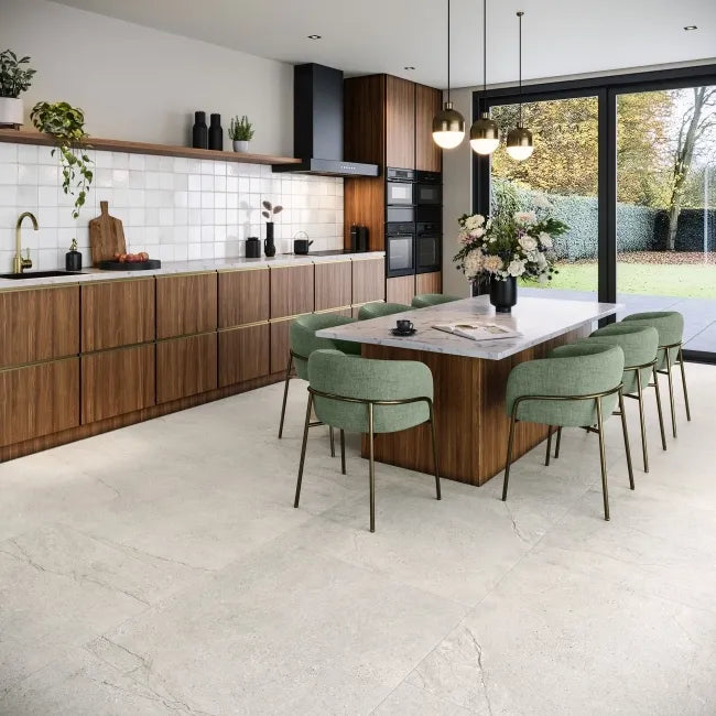 Driftwood Pale Grey 995x995mm concrete-style porcelain floor tiles in a modern kitchen with walnut cabinetry and green dining chairs