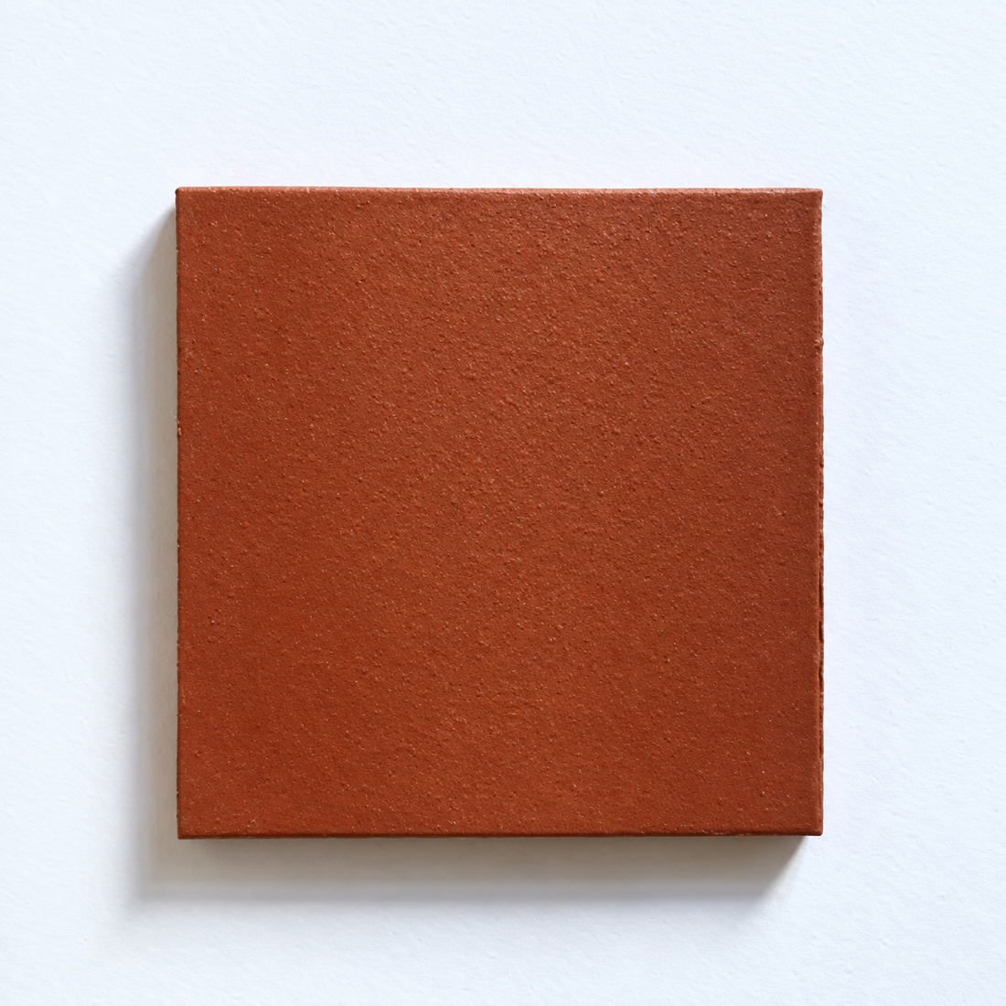 Deep red square quarry tile with a textured clay finish against a pale background