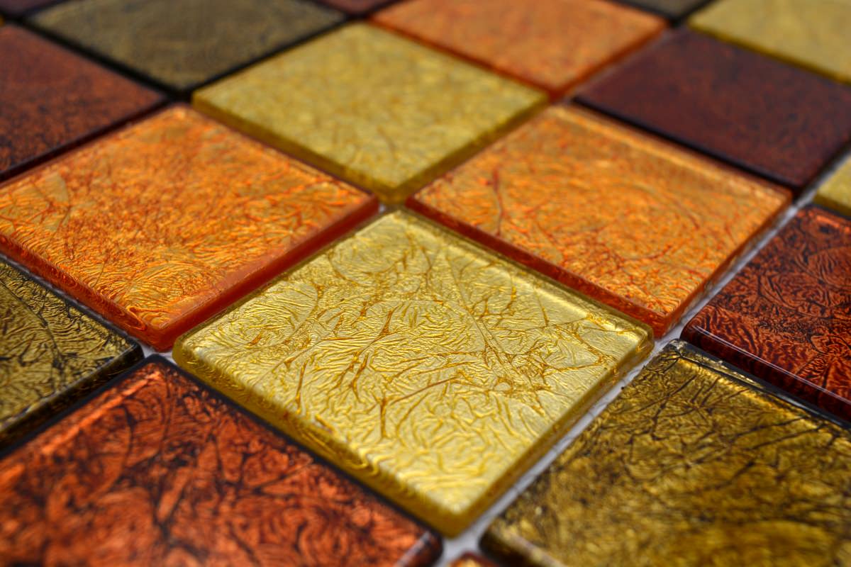 Angled close-up of gold, copper and bronze glass mosaic wall tiles with glossy leaf-effect texture