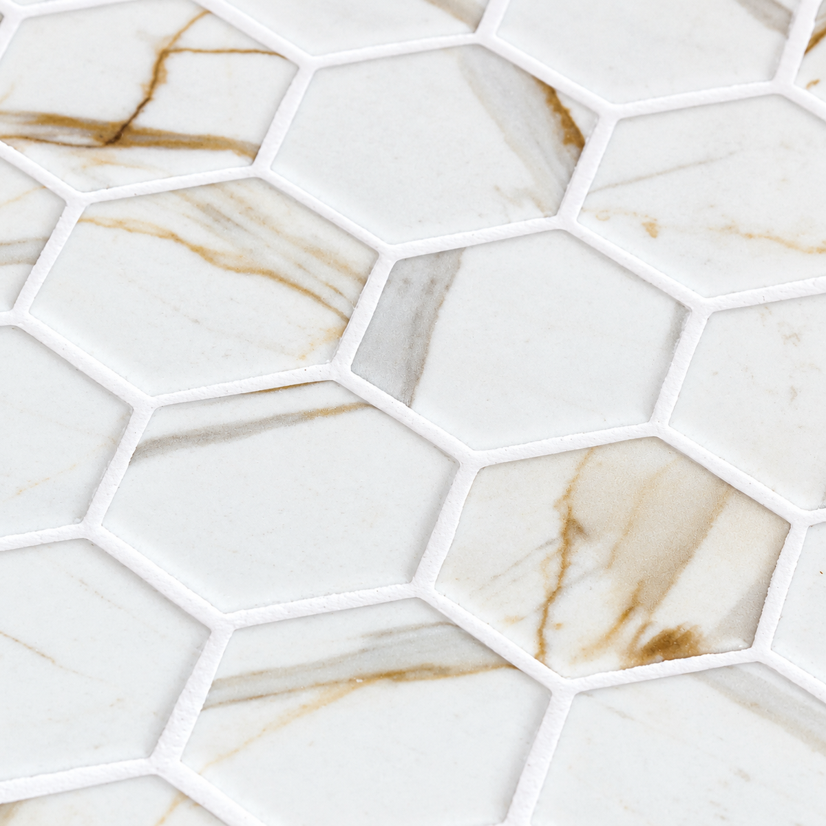 Close-up of Calacatta Gold matt glass hexagon mosaics with grey and gold veining and white grout.