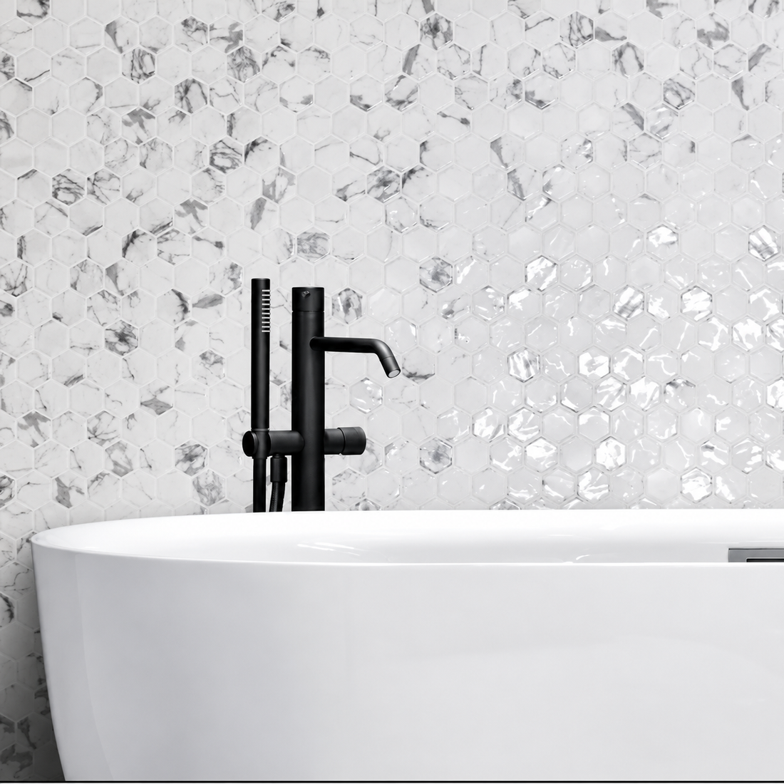 Hex XL Fosco white and grey marble-effect hexagon mosaic wall behind a freestanding bath with black tap.