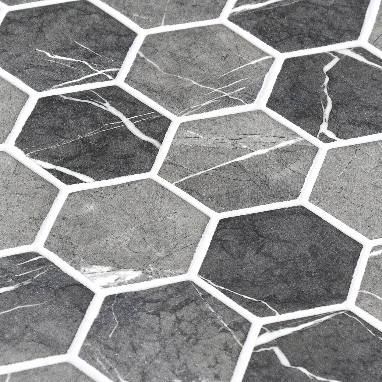Close-up of Hex XL Grafito grey hexagon glass mosaics showing the matt finish, white marble-effect veins and white joints.