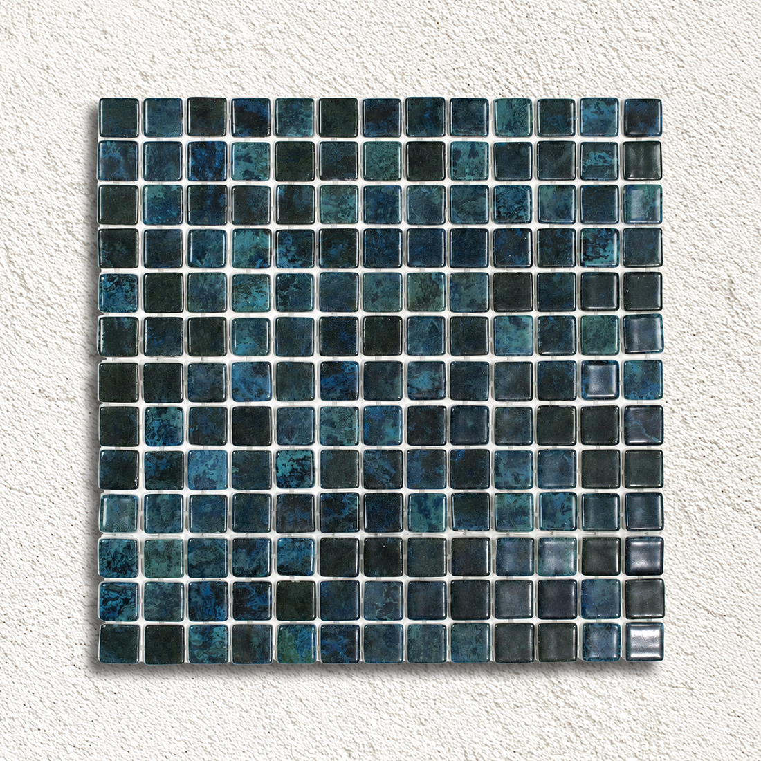 Karma Blue Moon glass mosaic sheet showing glossy 25mm squares in mottled dark blue, teal and charcoal.