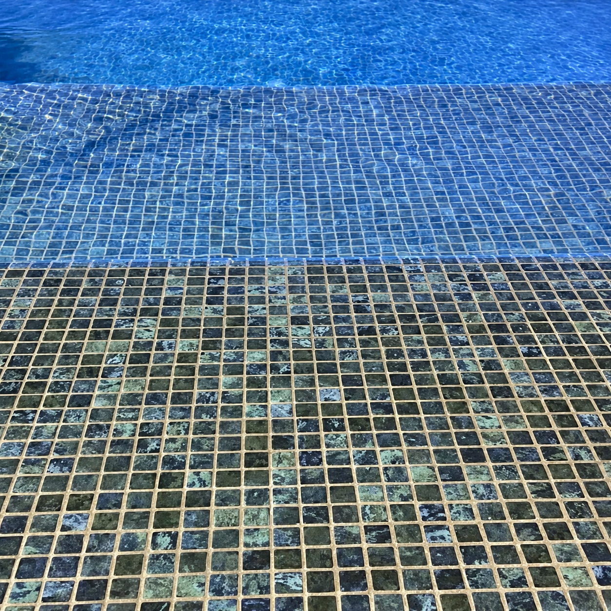 Karma Blue Moon glass mosaic sheet showing glossy 25mm squares in mottled dark blue, teal and charcoal.