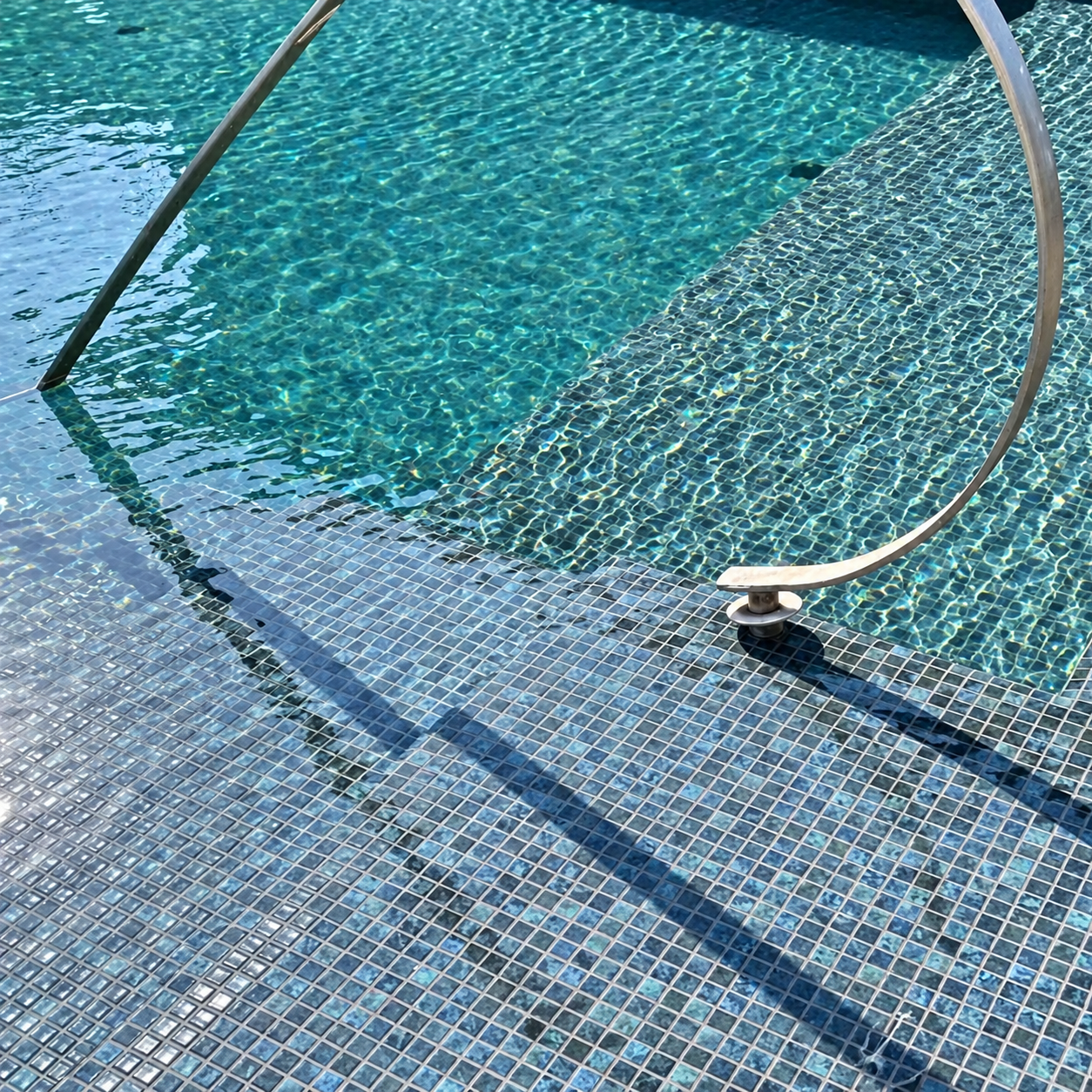  Karma Blue Moon glass mosaics lining an outdoor swimming pool with curved stainless steel handrails and turquoise water.