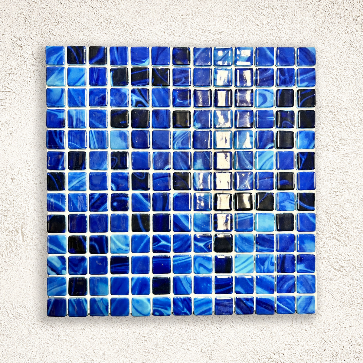 Karma Moana glass mosaic sheet with glossy cobalt and navy squares, aqua swirls and pale joints.