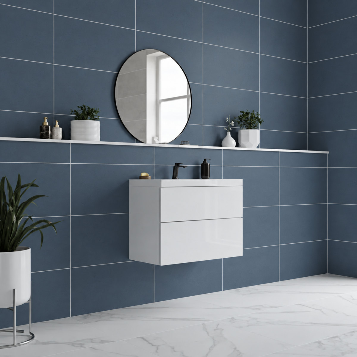 Liscio Avio slate blue matt wall tiles 600×300mm behind a white floating vanity and round mirror, with marble effect flooring