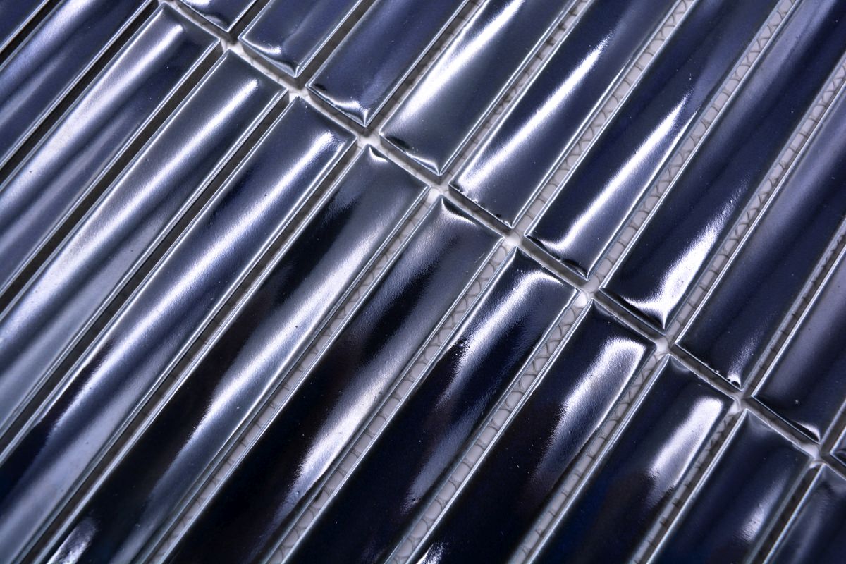 Macro image of dark navy glossy KitKat mosaic tiles showing rounded edges, reflective glaze and mesh-mounted joints
