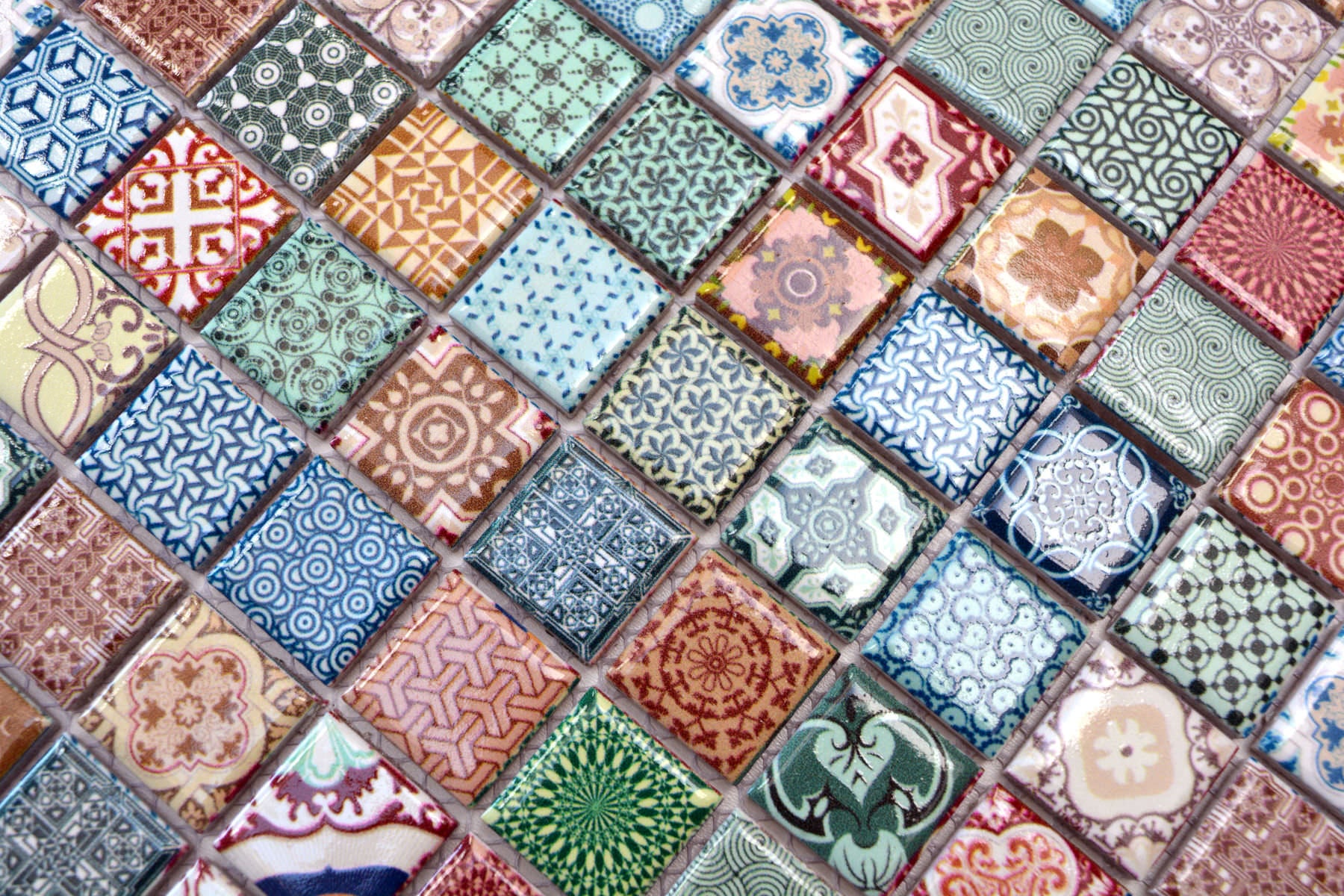 Detailed macro image of Moroccan ceramic mosaic tiles with multicolour geometric, floral and vintage-inspired patterns.