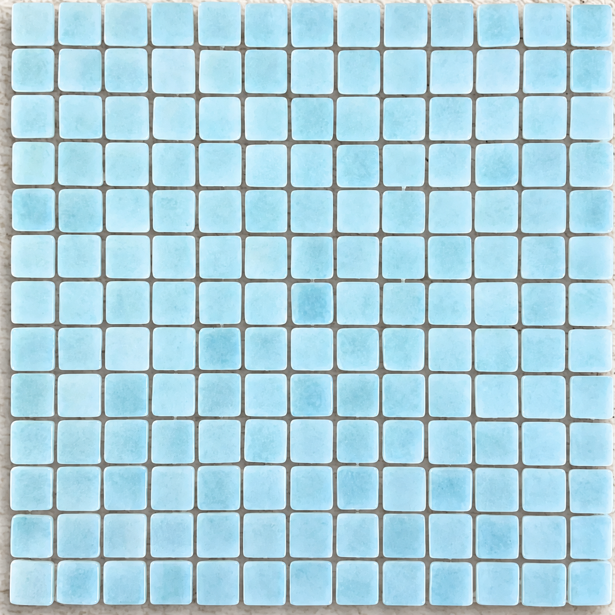 Detail of Niebla Foggy Aqua gloss glass mosaics showing cloudy pale blue markings and softly rounded square edges.