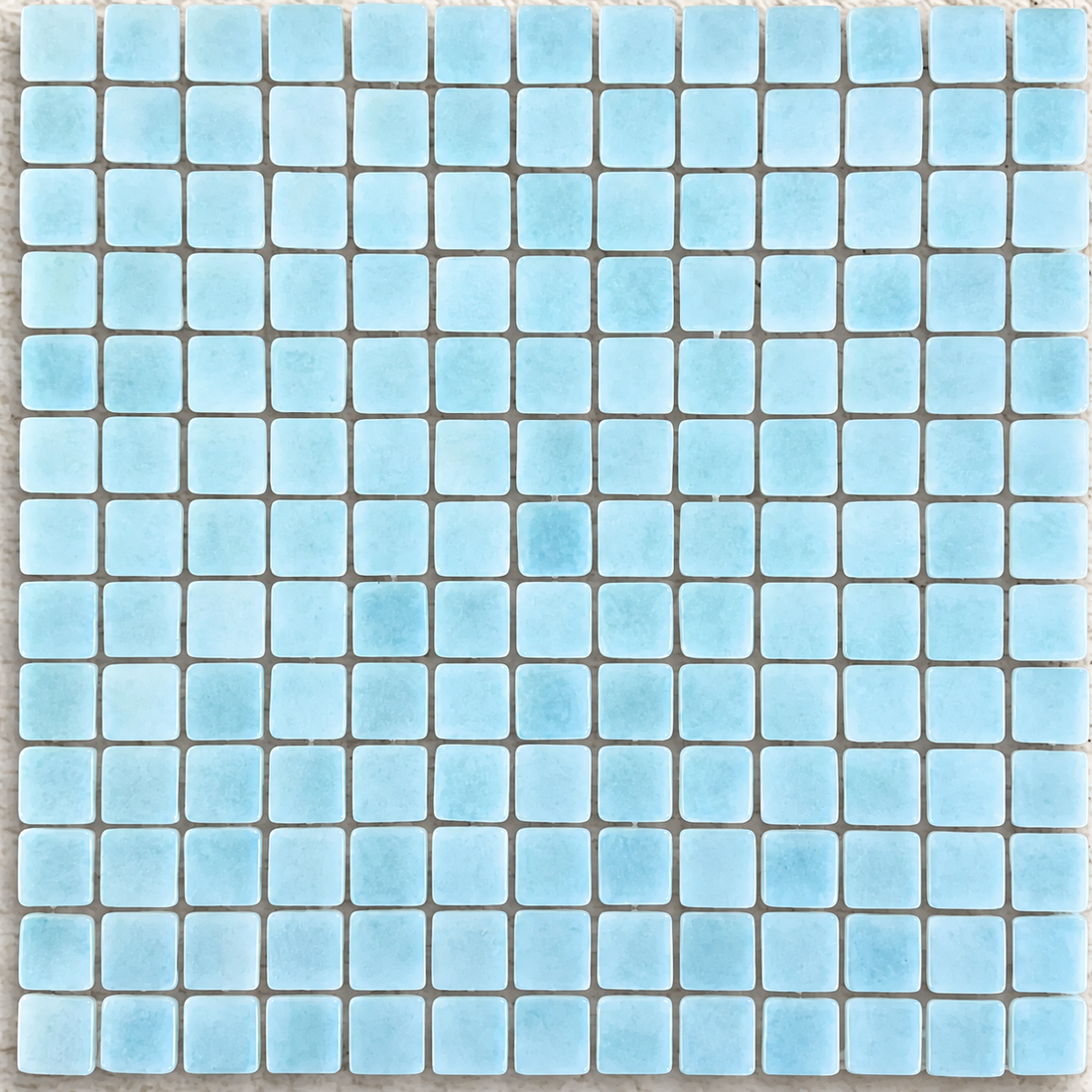 Detail of Niebla Foggy Aqua gloss glass mosaics showing cloudy pale blue markings and softly rounded square edges.