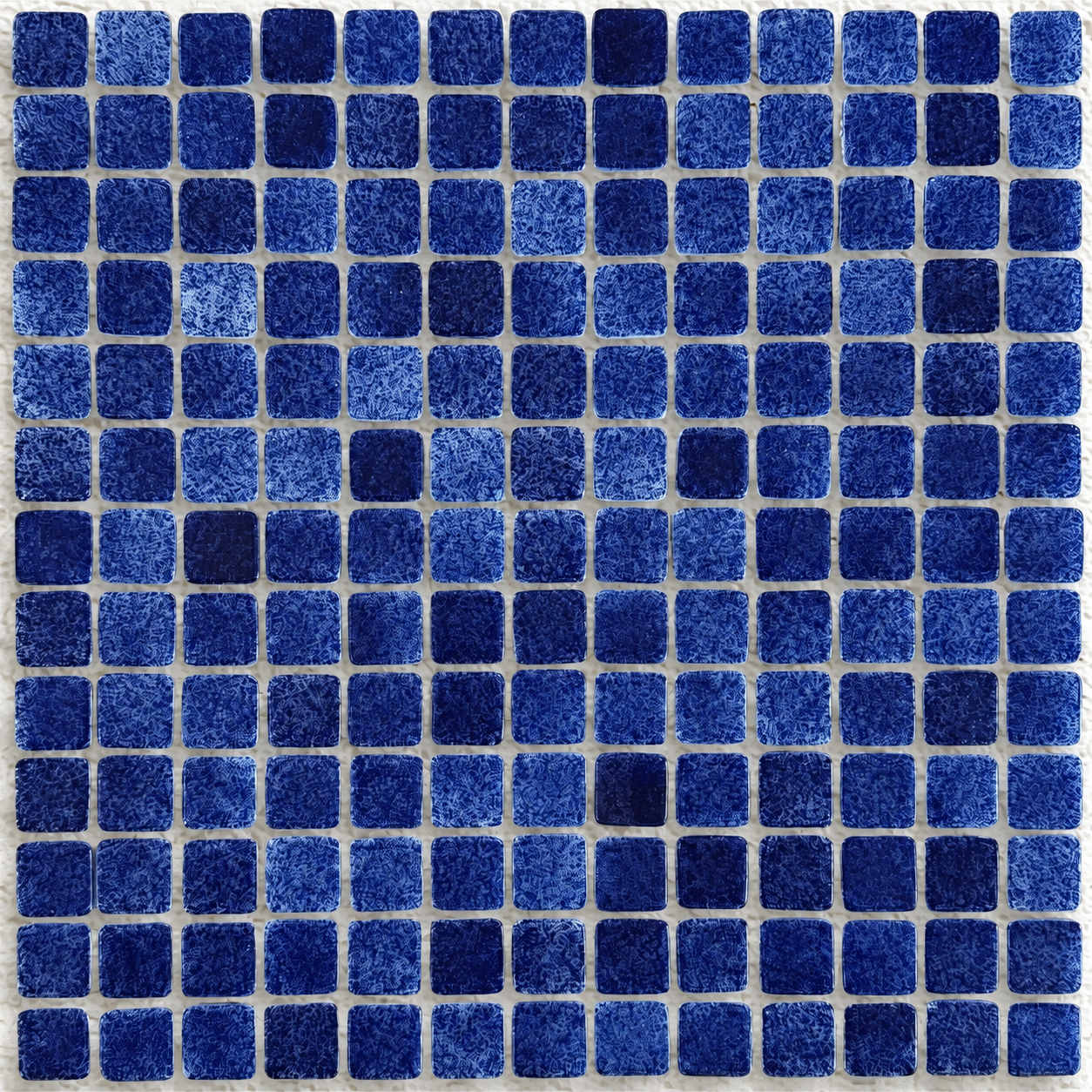 Close-up of Niebla Foggy Dark Blue mosaic tiles showing cloudy blue detailing and rounded square edges.