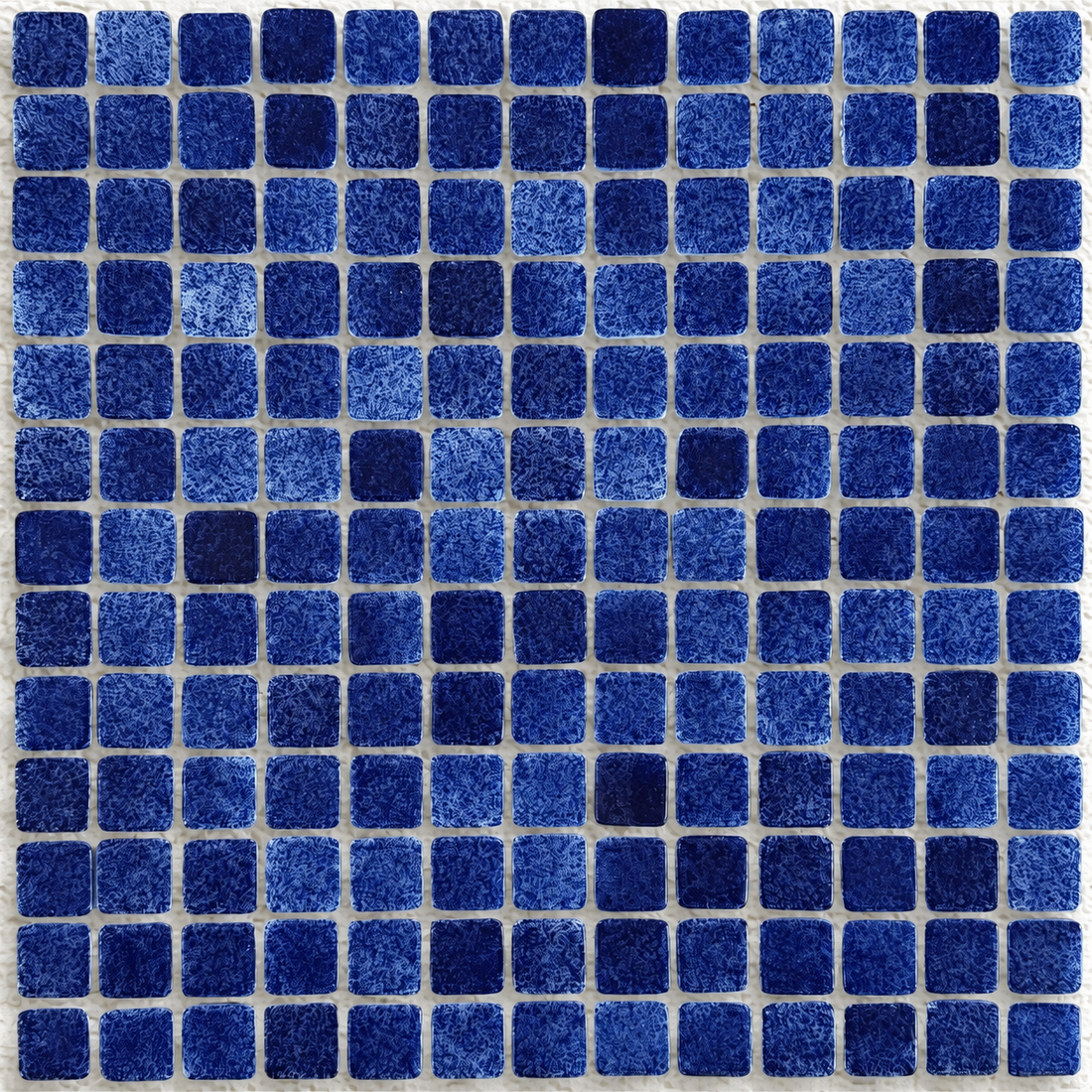 Close-up of Niebla Foggy Dark Blue mosaic tiles showing cloudy blue detailing and rounded square edges.