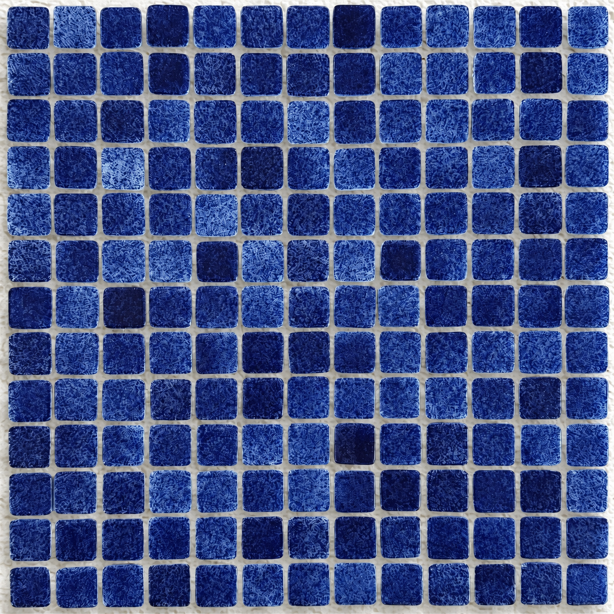 Close-up of Niebla Foggy Dark Blue mosaic tiles showing cloudy blue detailing and rounded square edges.