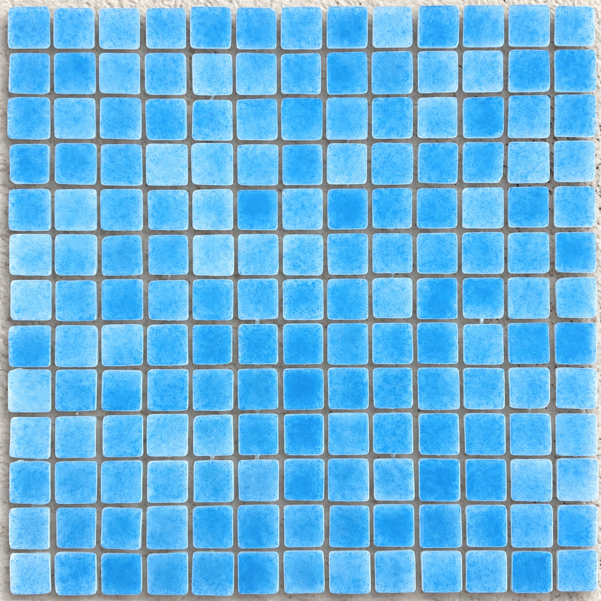 Close-up of Niebla Foggy Light Blue glass mosaic tiles showing cloudy blue detailing and rounded square edges.