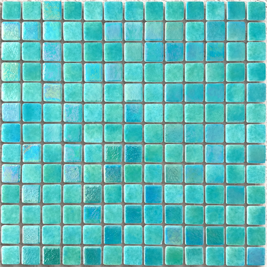 Close-up of Niebla Mix-Iris Indo 25mm square glass mosaics showing sea-green colour, mottled detailing and a lustre finish.