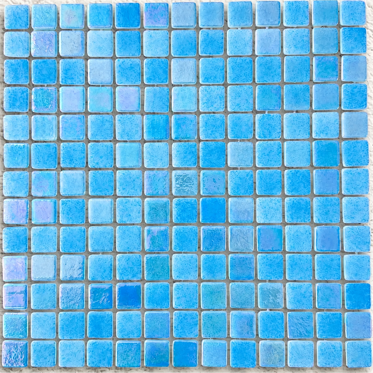 Close-up of Niebla Mix-Iris Oria glass mosaic tiles showing mottled blue tones, rounded corners and a lustre finish.