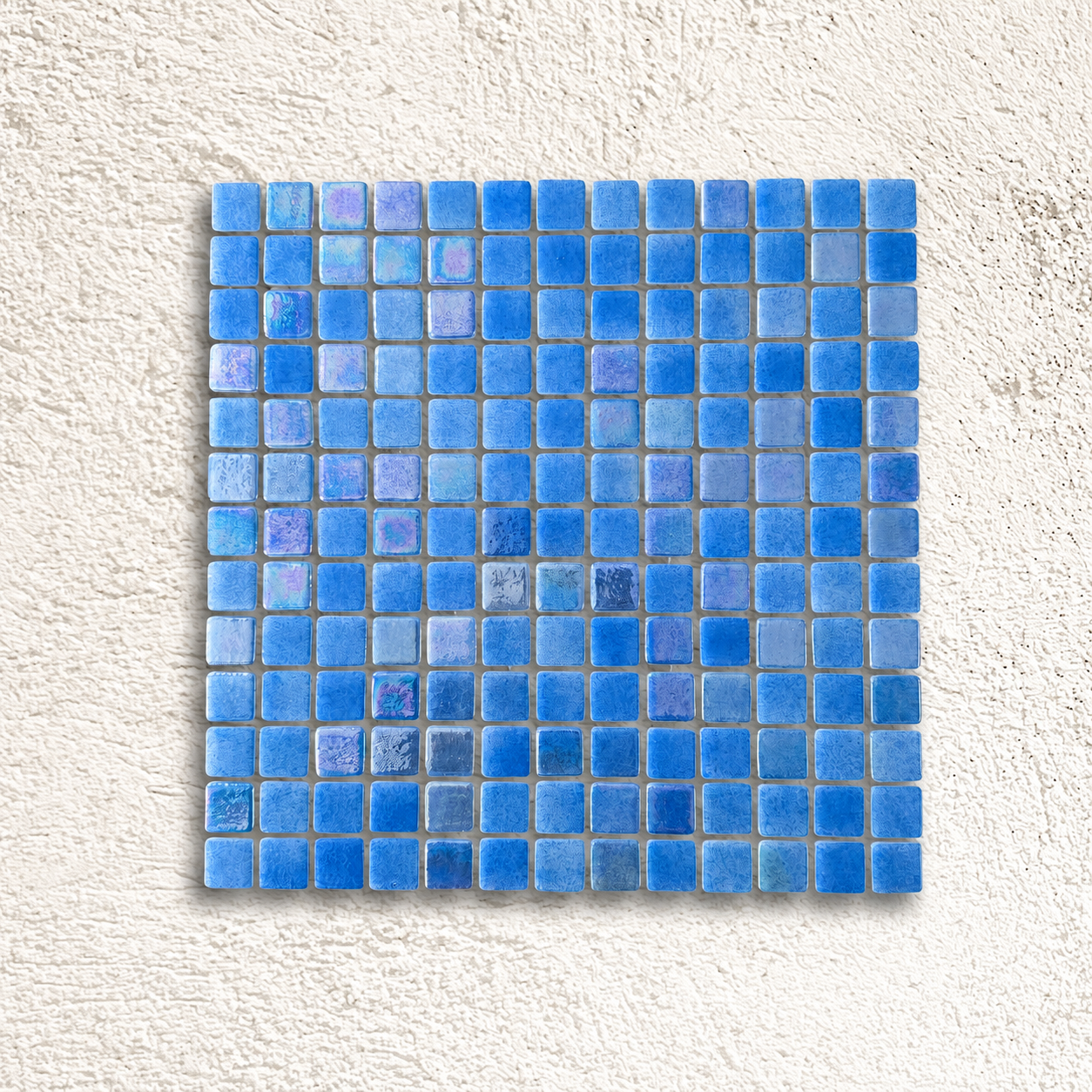 Niebla Mix-Iris Urumea blue glass mosaic sheet with iridescent lilac and aqua highlights on a white textured background.
