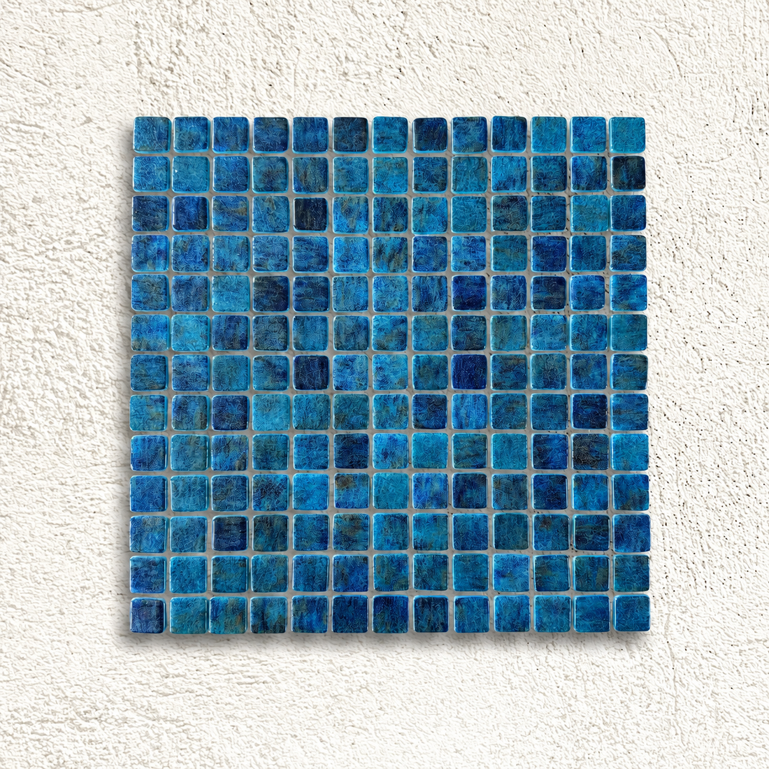 Niebla Paradise Zafiro glass mosaic sheet with 25mm sapphire blue squares on a white textured background.