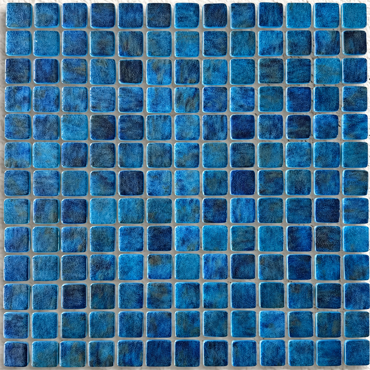 Detail of Niebla Paradise Zafiro gloss glass mosaics showing navy and turquoise mottling and rounded square edges.