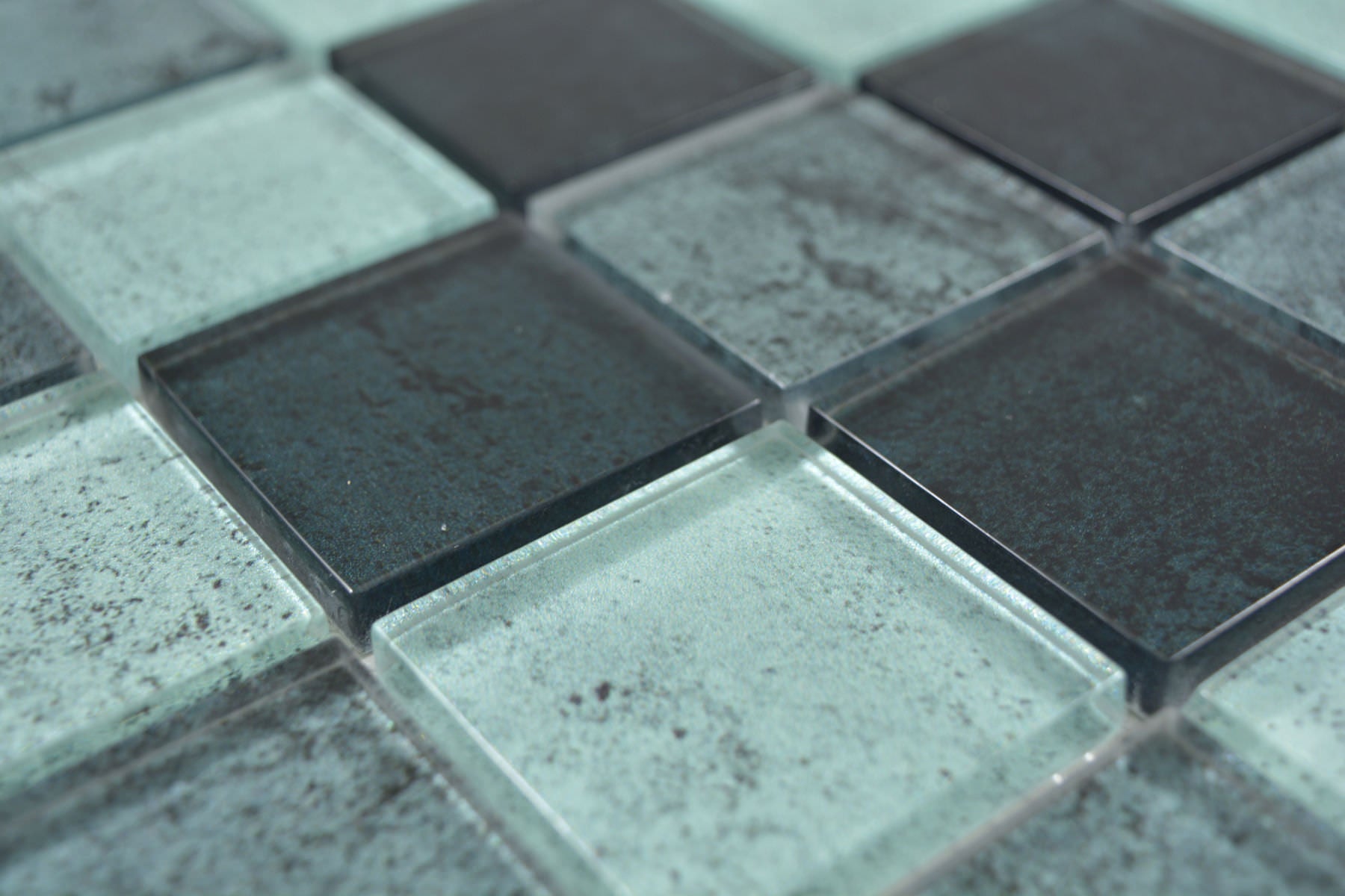 Angled view of Raindrop square green glass mosaic showing glossy surfaces, mottled detailing and 8mm thickness.