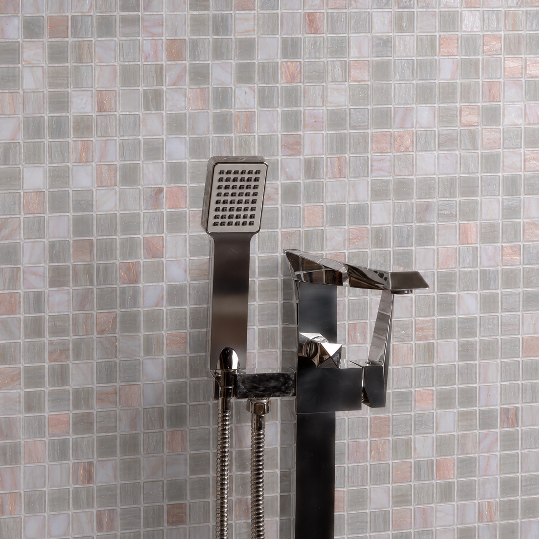 Modern chrome bath filler and handheld shower in front of pink, grey and silver 20mm square glass mosaic wall tiles.