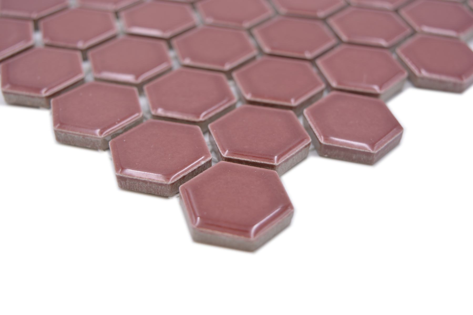 Angled close-up of Shapes burgundy red hexagon mosaic tiles showing glossy edges and ceramic thickness.