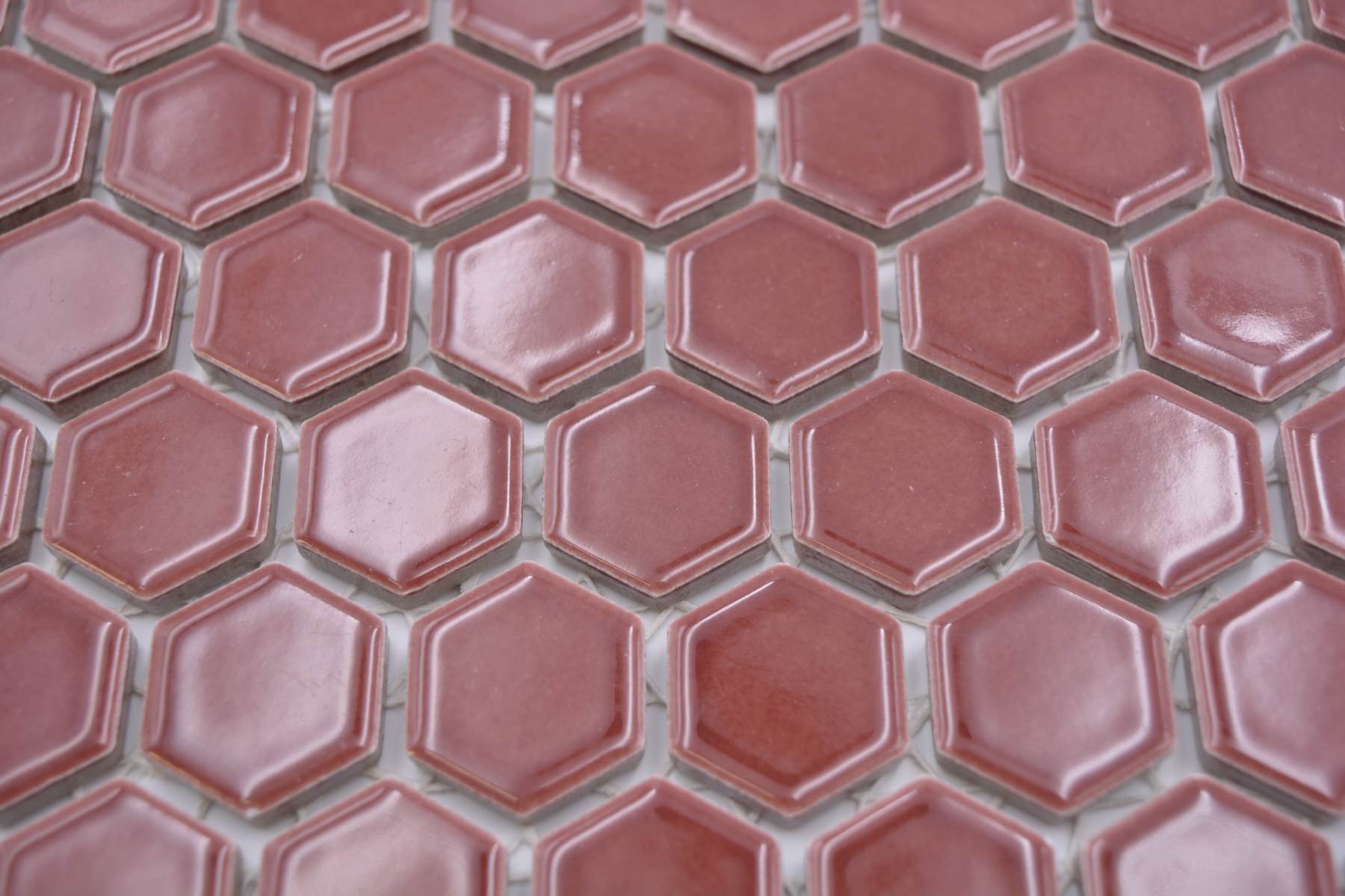 Close-up of Shapes burgundy red hexagon mosaic showing reflective glaze and softly contoured tile edges.