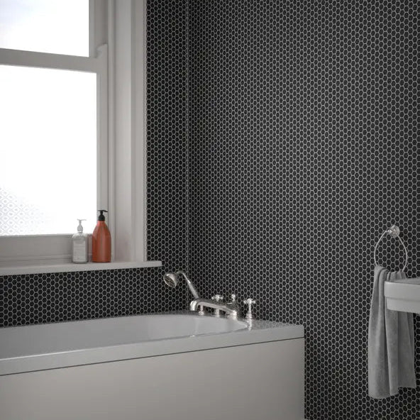 Shapes black hexagon mosaic tiles installed on a bathroom wall and bath surround with white sanitaryware.