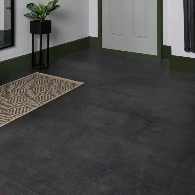 Stone Effect Anthracite LVT flooring installed in a hallway with green skirting, white walls and patterned rug
