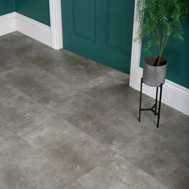 Stone Effect Grey LVT flooring installed in a hallway with teal walls, white skirting boards and a potted plant.