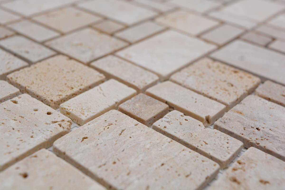 Close-up of ivory travertine mosaic tile with mixed square and rectangle stone chips