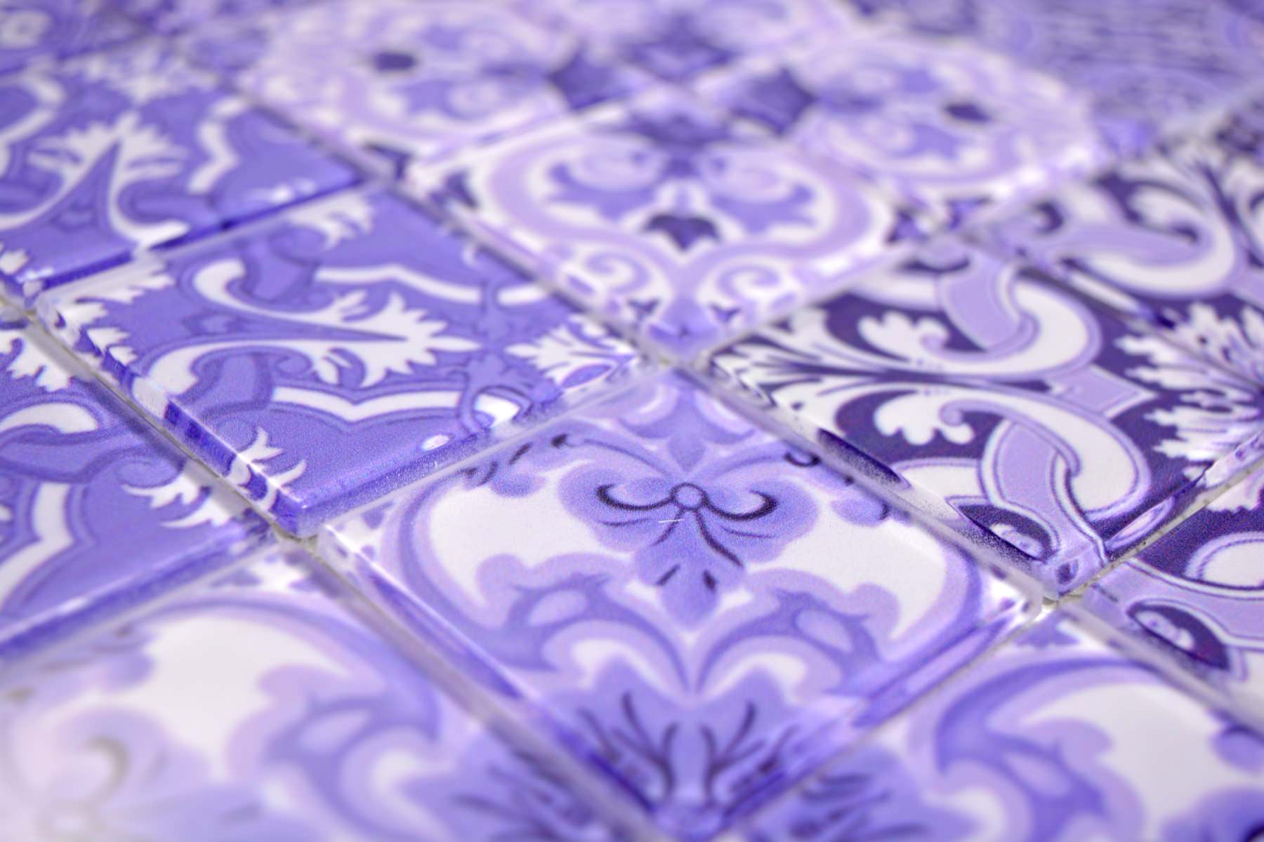 Angled detail of purple and white patterned glass mosaic tiles with raised glossy surface and ornate retro motifs